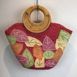 Donna Dixon round rattan handle straw tote with appliquéd leaves.